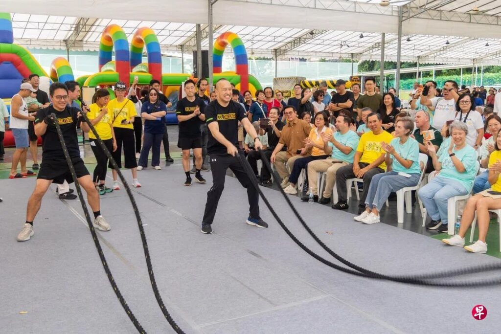 CDL Group Chief Executive Officer Sherman Kwek (right) joined employees in competing to complete the highest number of battle rope swings as part of the fundraising challenge. Minister for Digital Development and Information Mrs Josephine Teo (seated, third from right) and Assisi Hospice Patron Ho Ching (seated, second from right) were also present to show their support. Photo by Lianhe Zaobao.